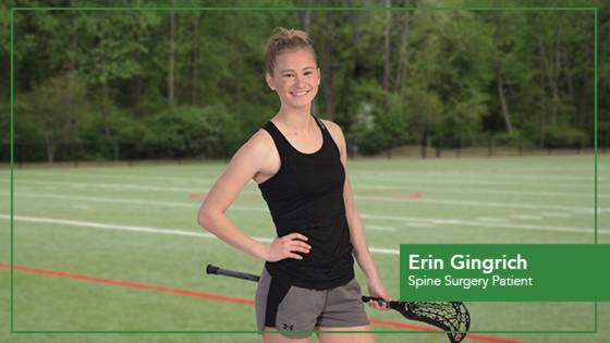 Girl with hand on her hip holding a lacrosse racket.