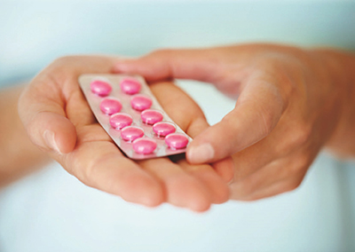 Pill pack with pink pills held in hand