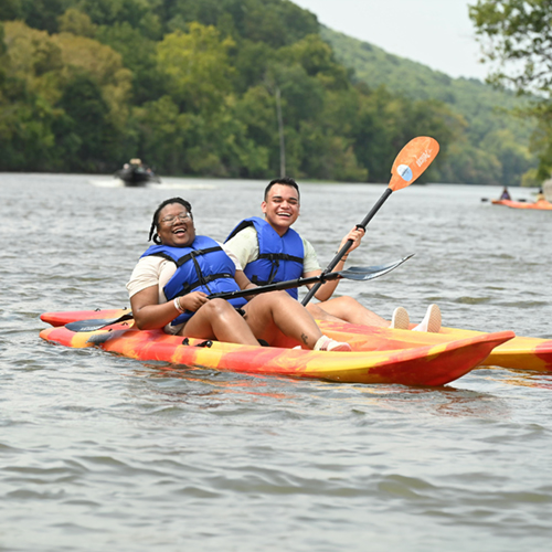 Two kids kayaking while wearing USCG-approved life jackets