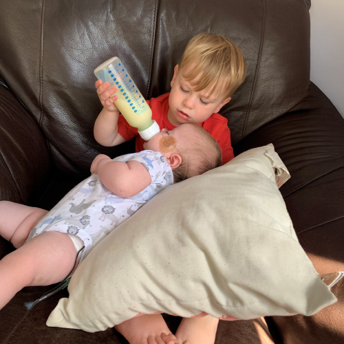 Baby Pierce enjoys a bottle fed by Big Brother