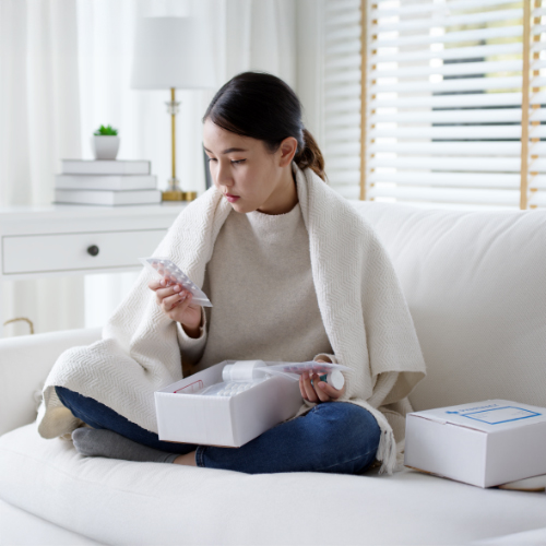 Woman on couch reviewing her prescription delivery.