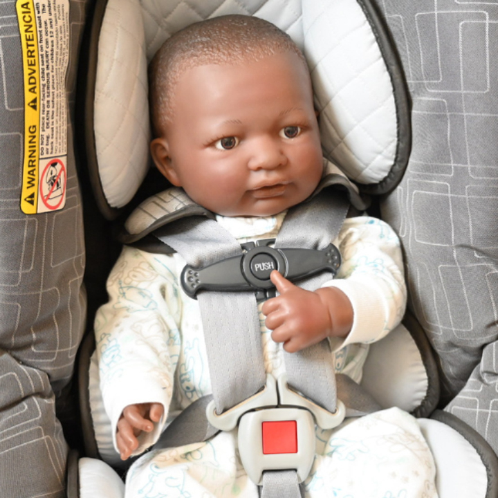 A baby doll safely strapped in a car seat for demonstration purposes.