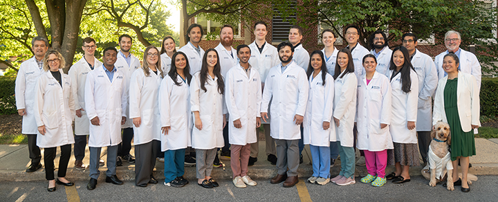 Group of psychiatry residents and teaching faculty posing in white medical coats outside hospital
