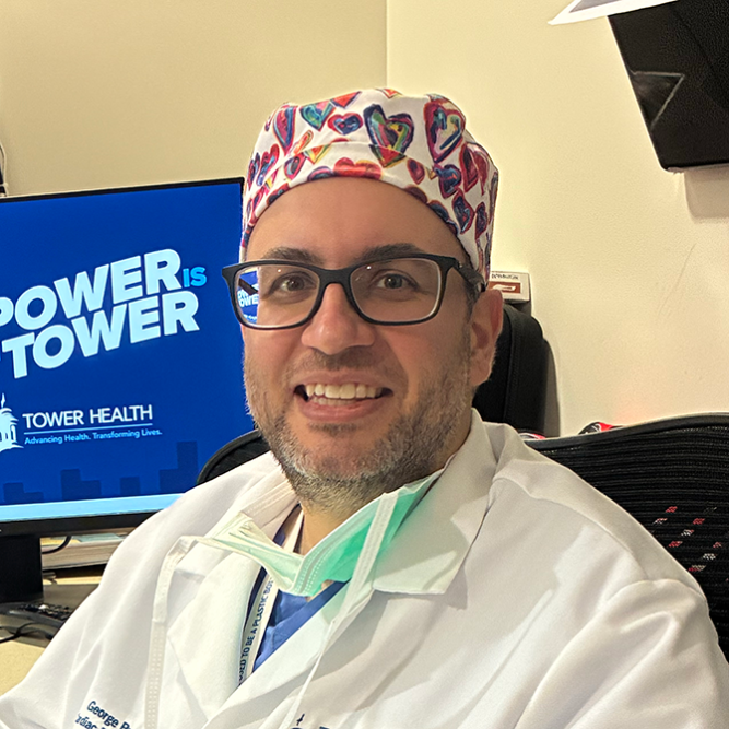 George Prousi, MD, in surgical coat and scrubs