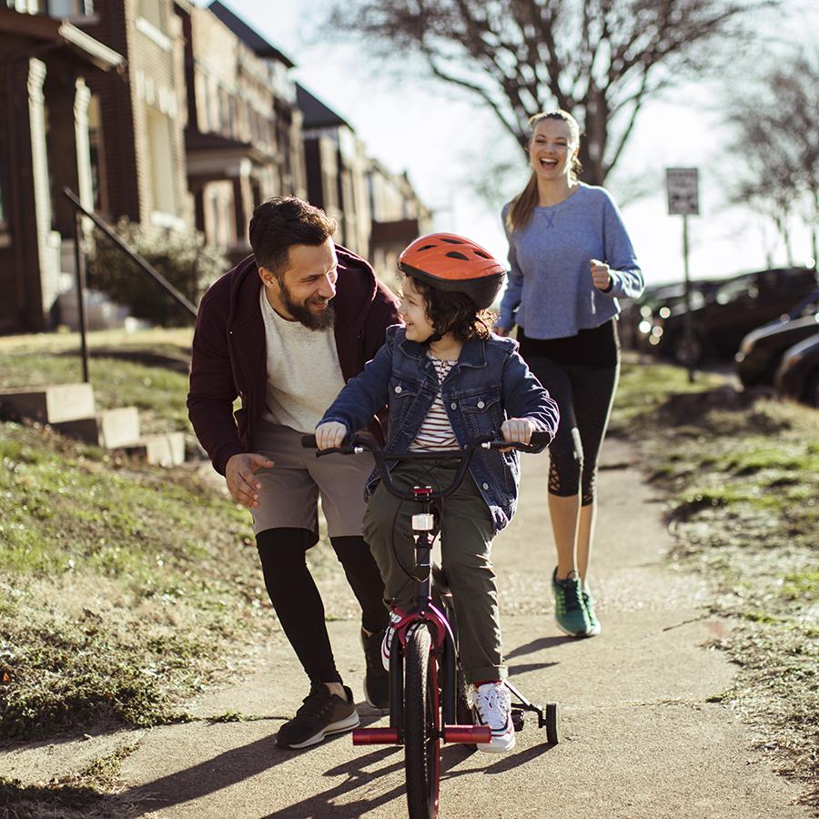 active parents help teach child to ride bike