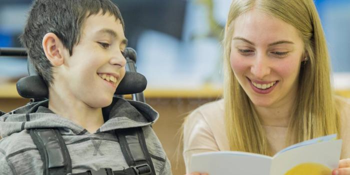 Volunteer reading to boy in wheelchair