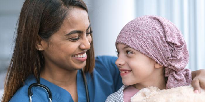 nurse smiling next to girl with cancer. Tower Health Pediatric Cancer Care