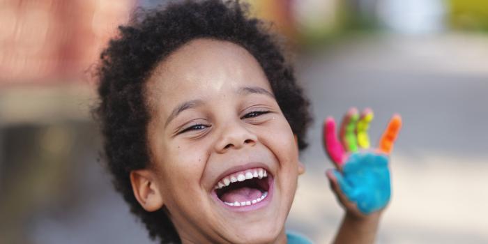 smiling boy with colorful paint on his hand 