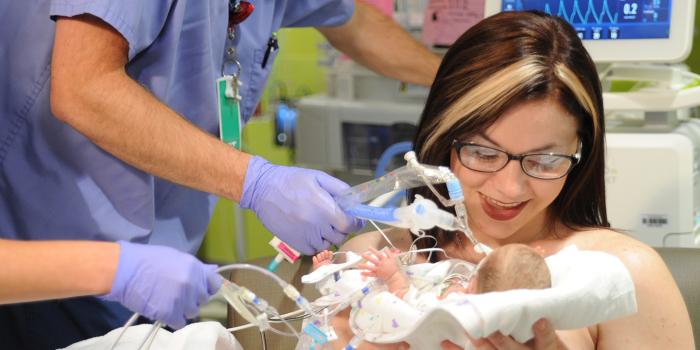 mother with baby in the NICU with doctors surrounding her