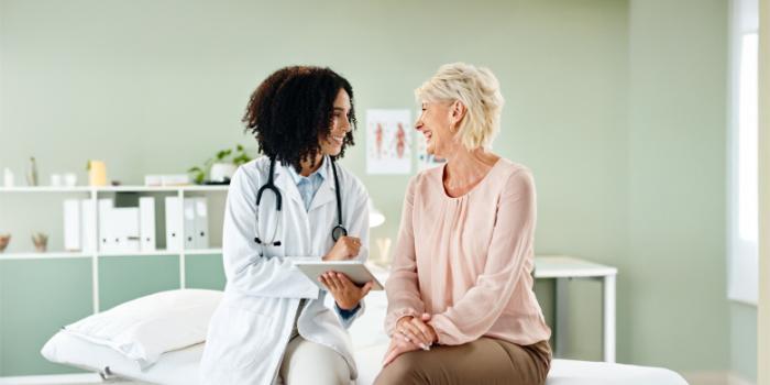 An older female patient and her doctor smile as they discuss her health.